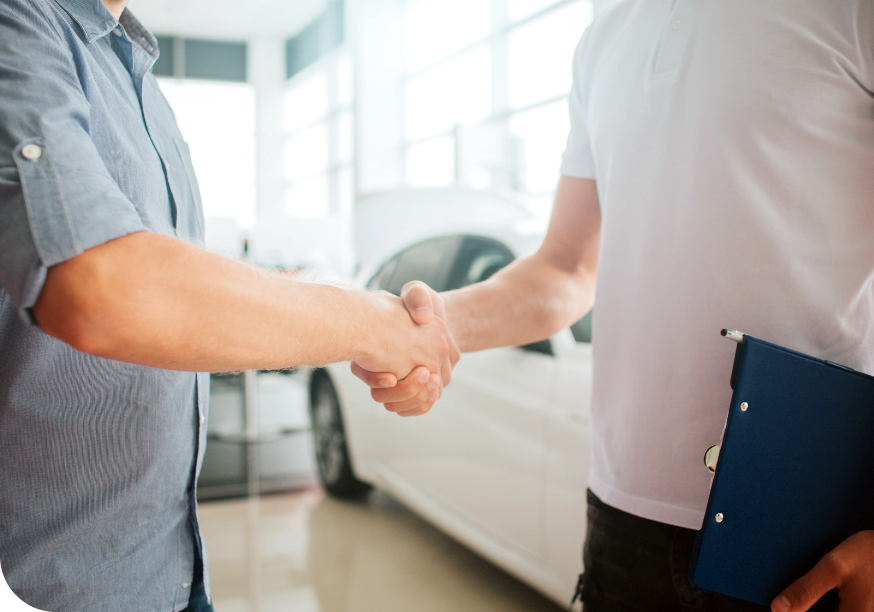a man shaking hands with another man in a car dealership