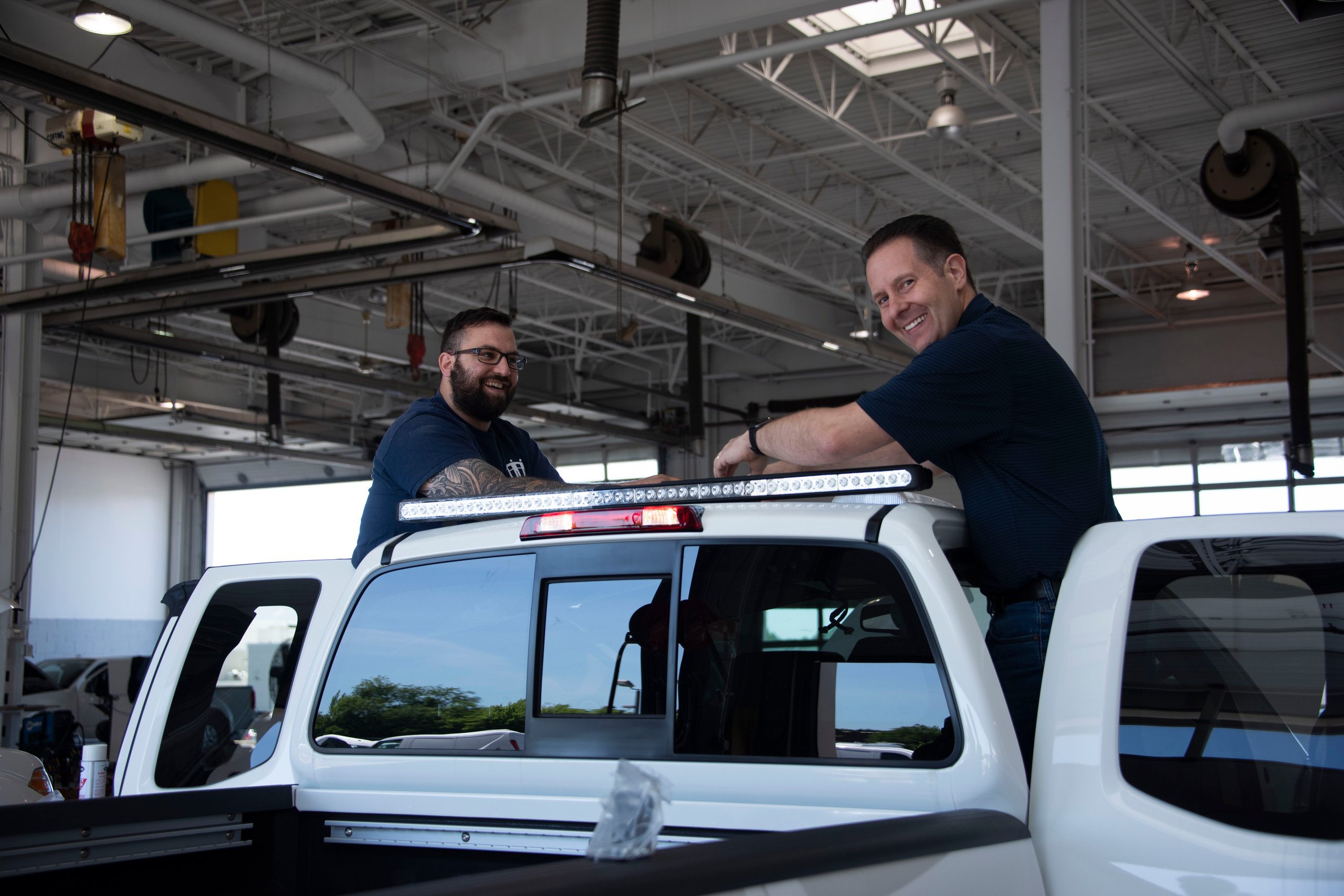 two men standing on top of a white truck