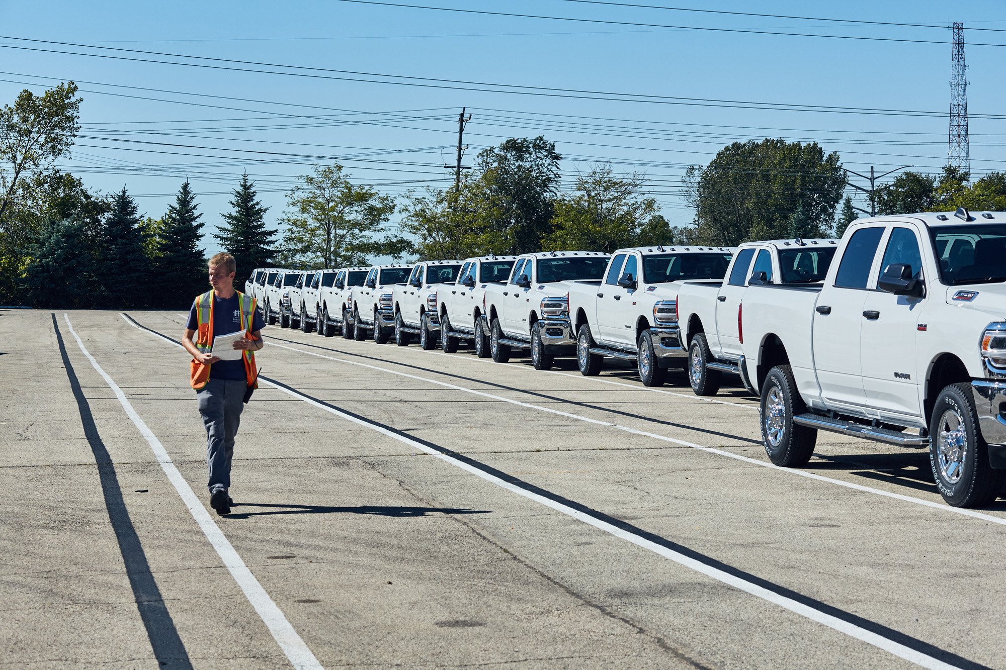 a woman walking on a road with a row of white pickup trucks