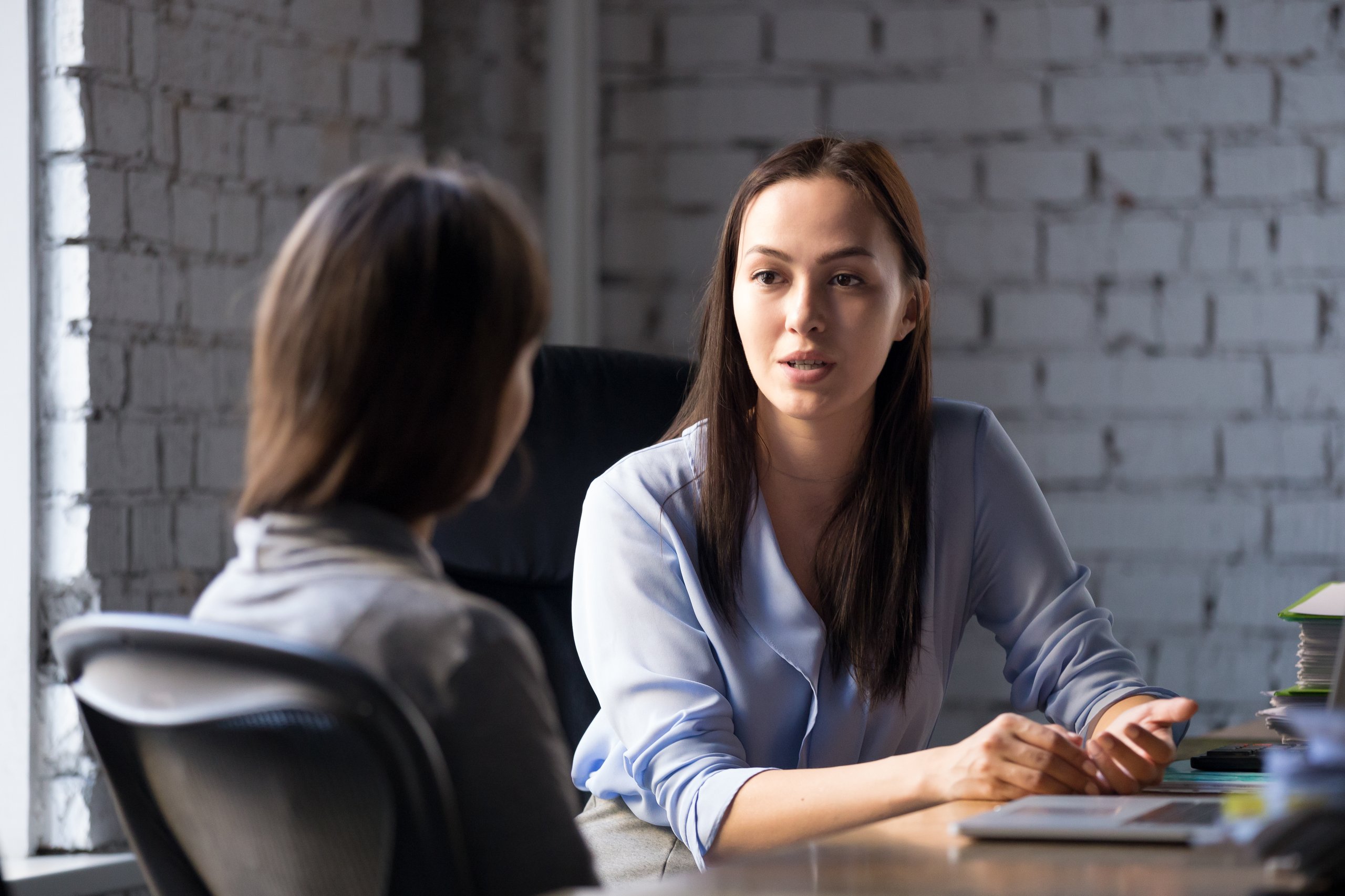 a woman sitting at a table talking to another woman