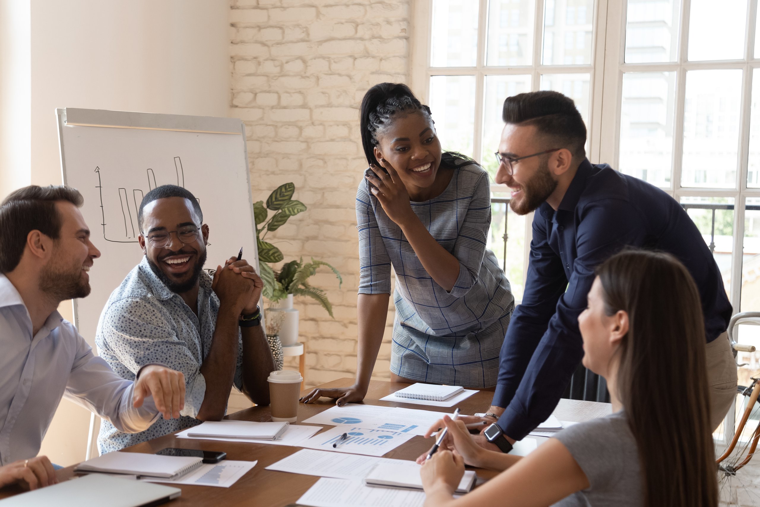 A group of people smiling in the office while discussing statistics