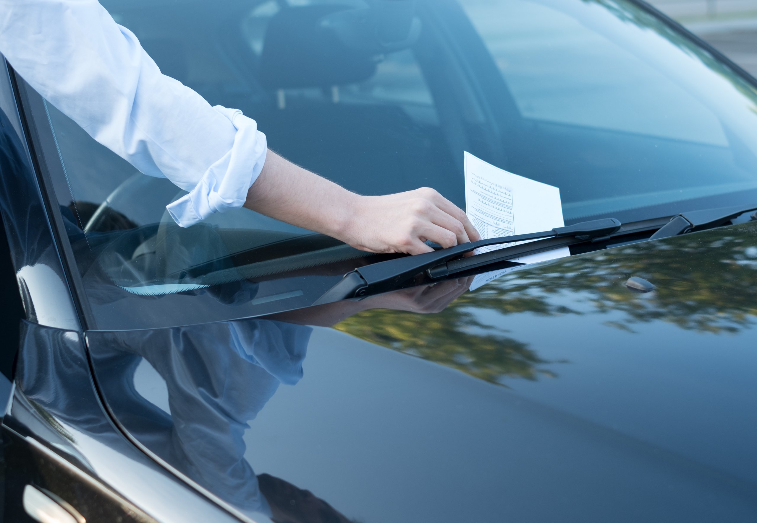 a person holding a piece of paper on a car