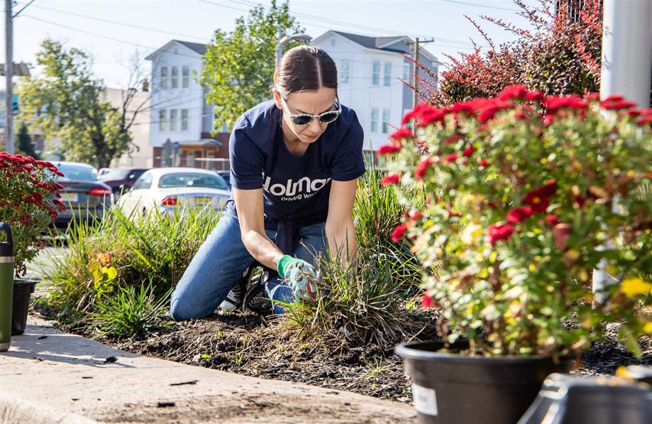a woman in sunglasses kneeling in a garden