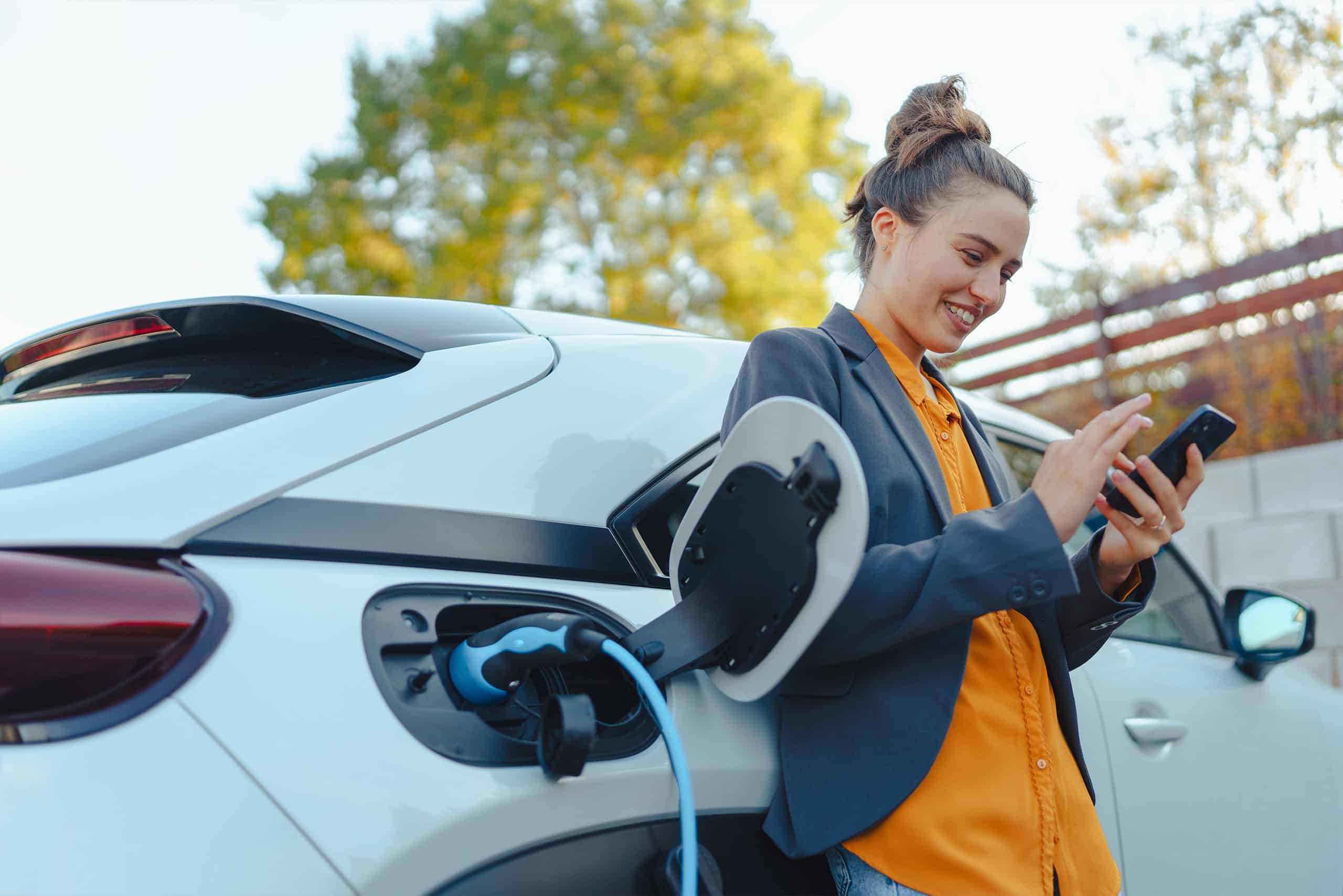 a woman holding a phone next to a car