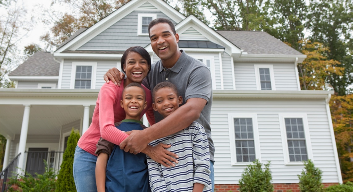 a family posing for a picture in front of a house
