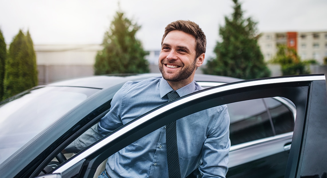 a man smiling and leaning on a car door