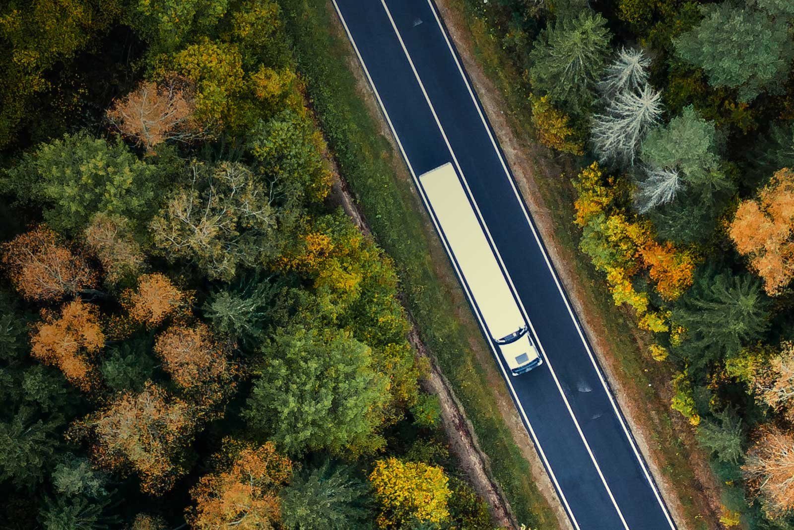 a truck driving on a road with trees 