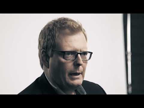 a man wearing glasses and a black suit