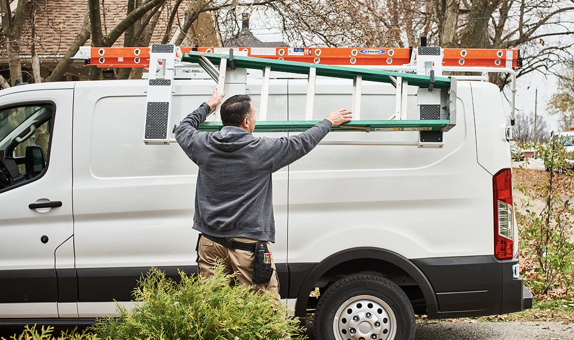 a man holding a ladder over a van