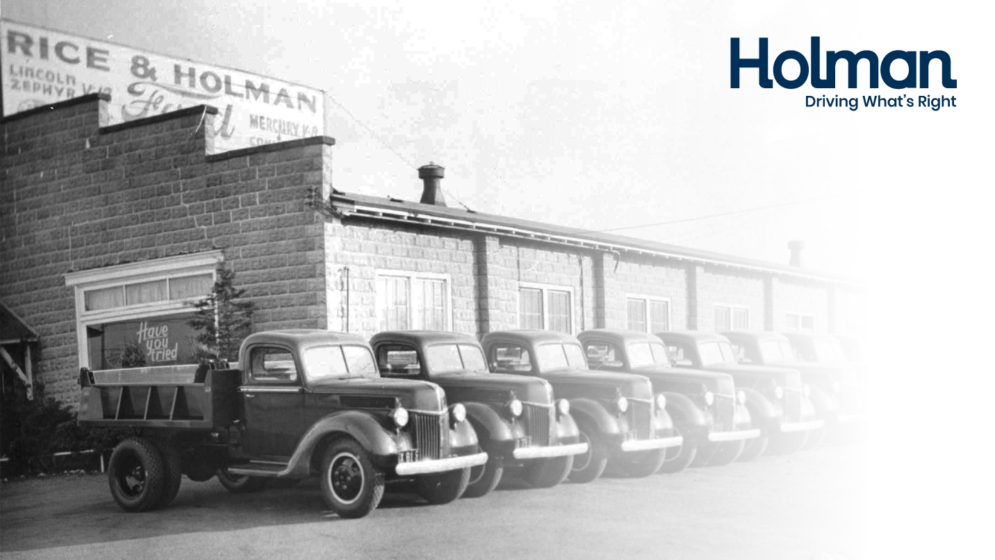 Fleet of work trucks parked in front of a dealership.