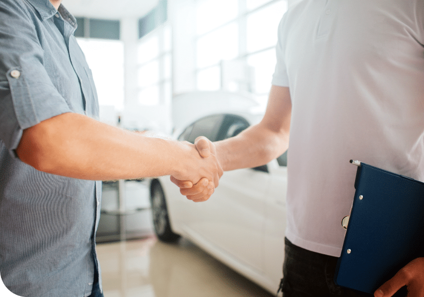 a man shaking hands with another man in a car dealership