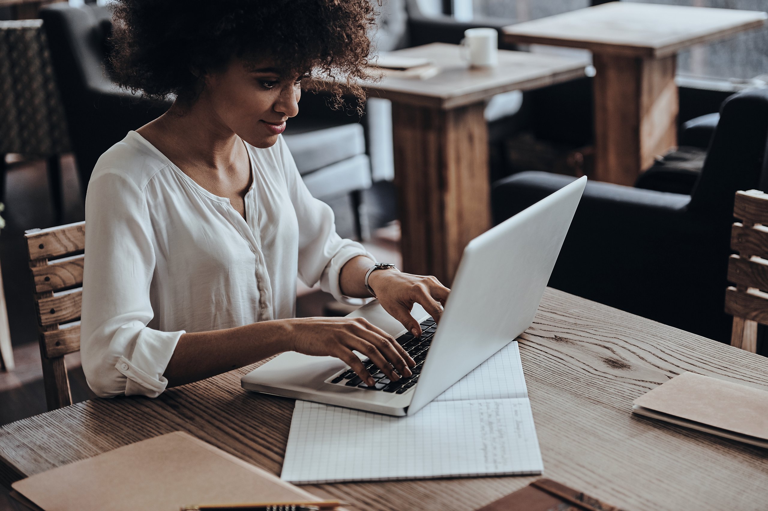 a woman sitting at a table typing on a laptop