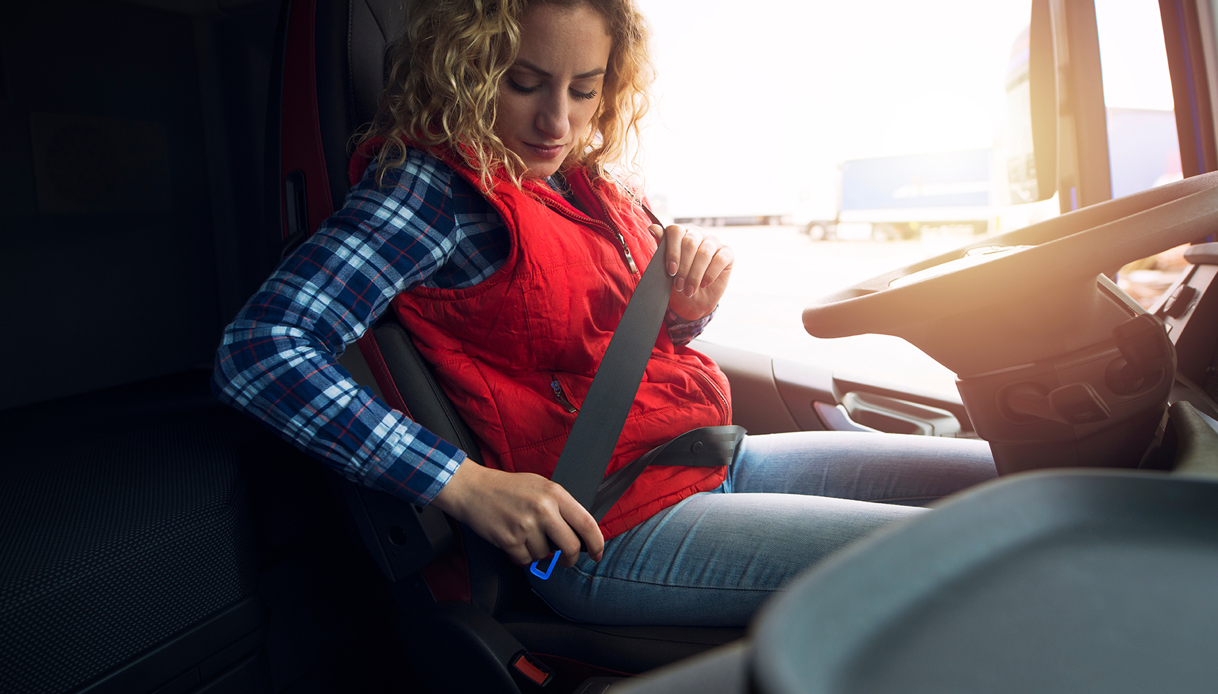 a woman sitting in a car fastening a seat belt