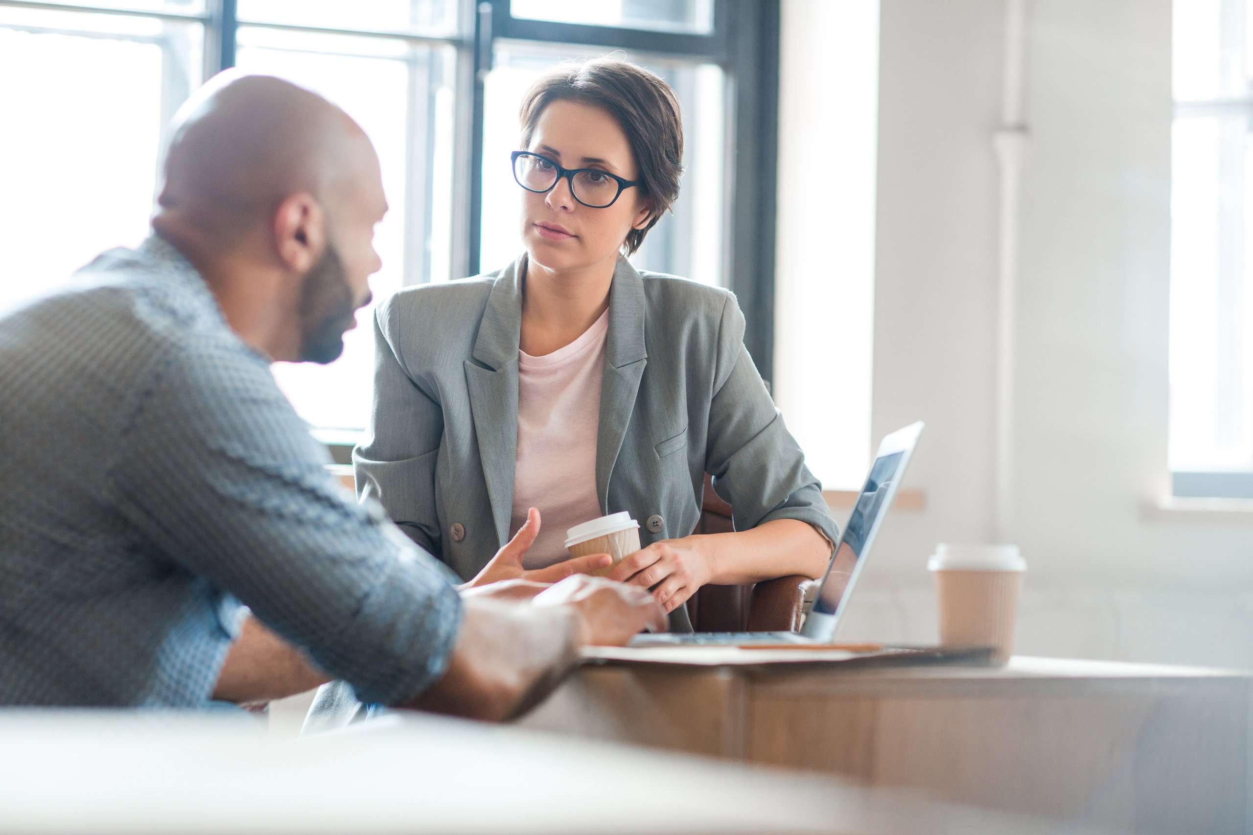 a man and woman sitting at a table with a laptop