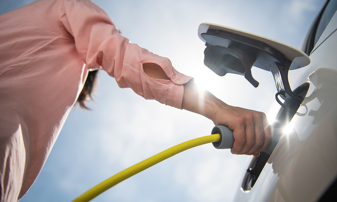 a person holding a hose to a car