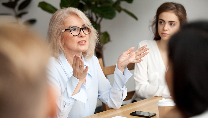 a woman sitting at a table with her hands raised