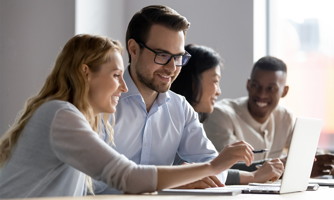 a group of people sitting at a table looking at a laptop