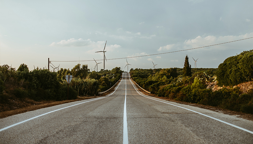 a road with wind turbines in the background