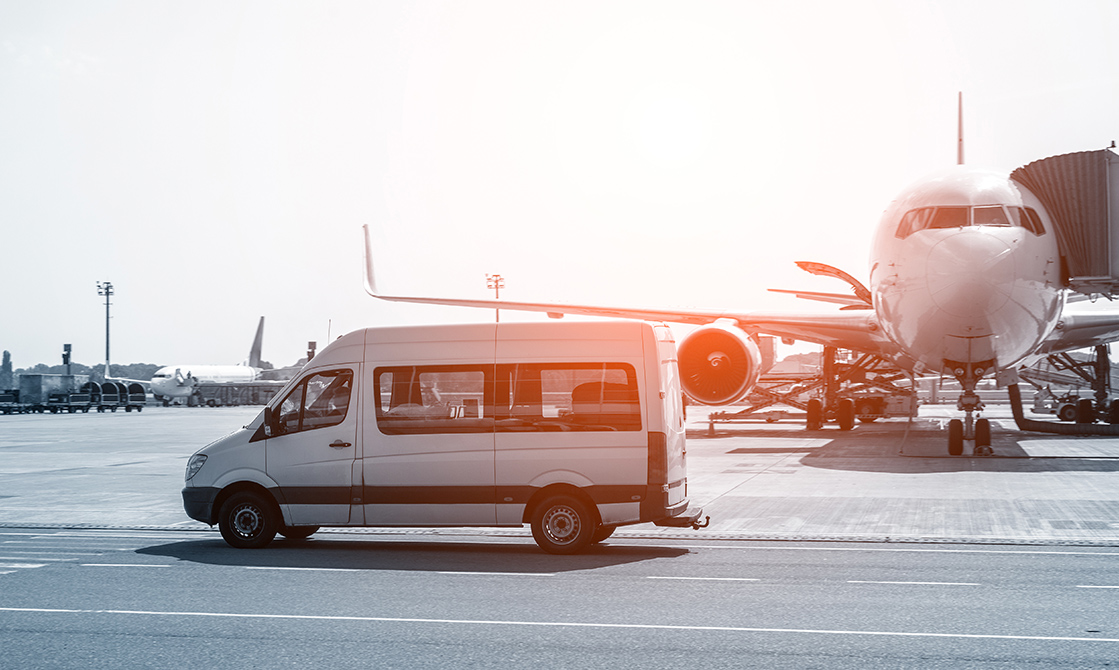 a white van and an airplane on a runway