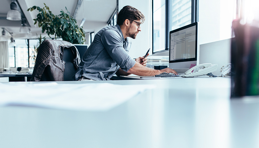 a man sitting at a desk looking at a computer