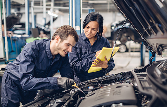 a man and woman working on a car
