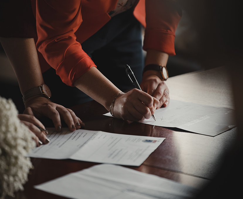 a person signing papers on a table