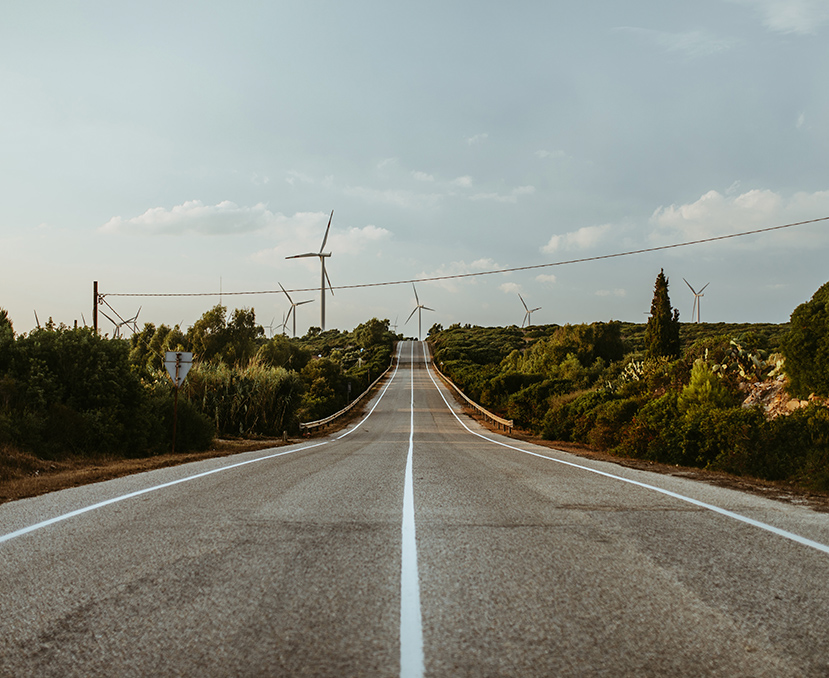 a road with wind turbines in the background