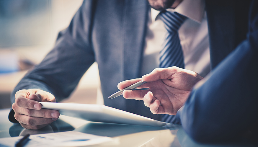 a man in a suit holding a pen and looking at a tablet