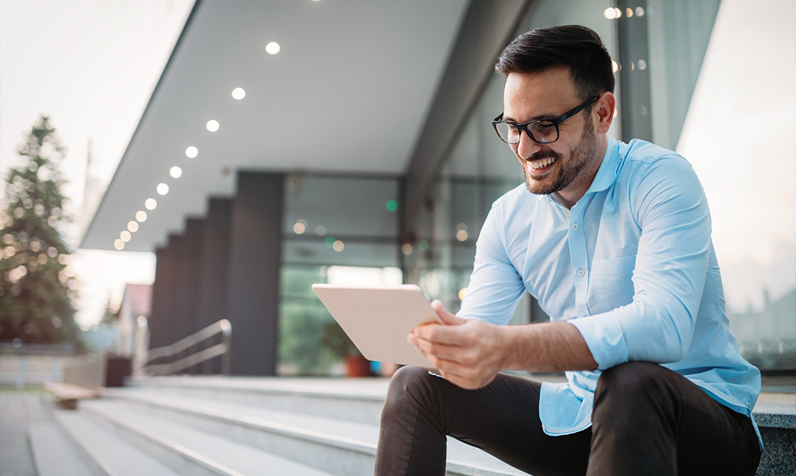 a man sitting on a bench looking at a tablet