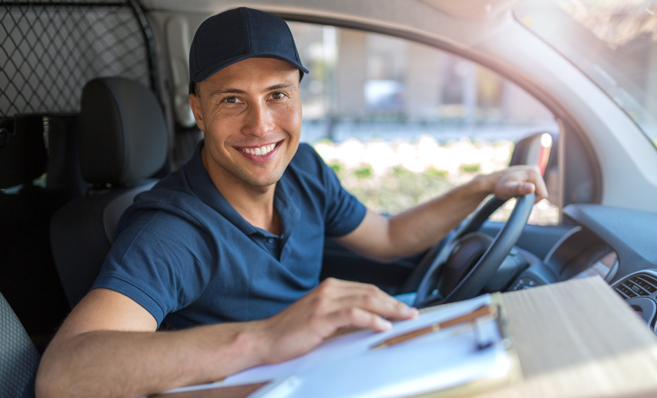 a man in a blue shirt and cap sitting in a car smiling