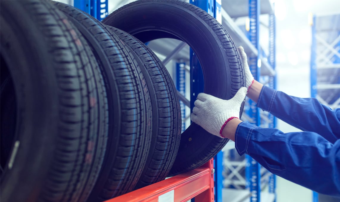 A person grabbing a tire off of a rack