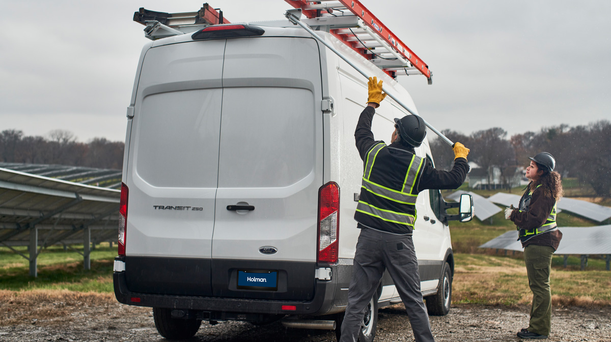 Two workers loading up a white van on a solar farm.