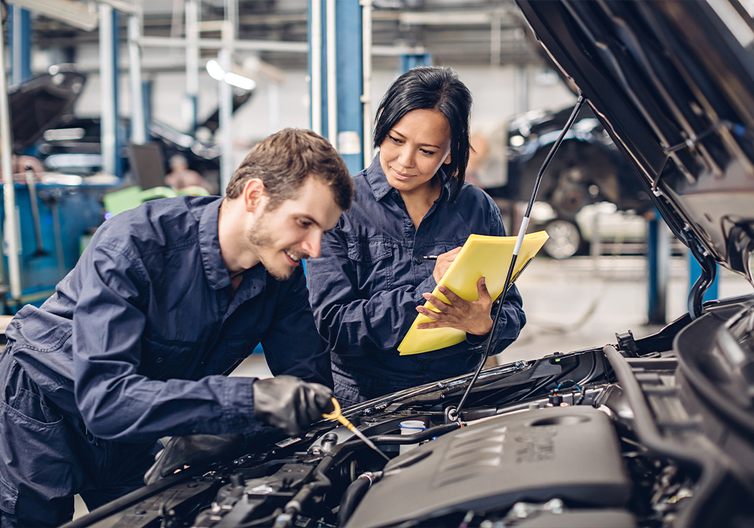 a man and woman working on a car engine