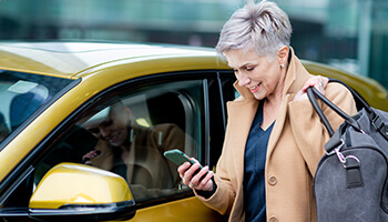 A person looking at a cell phone next to a car