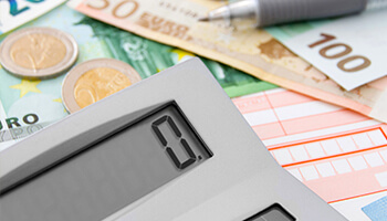 A calculator with money in the background