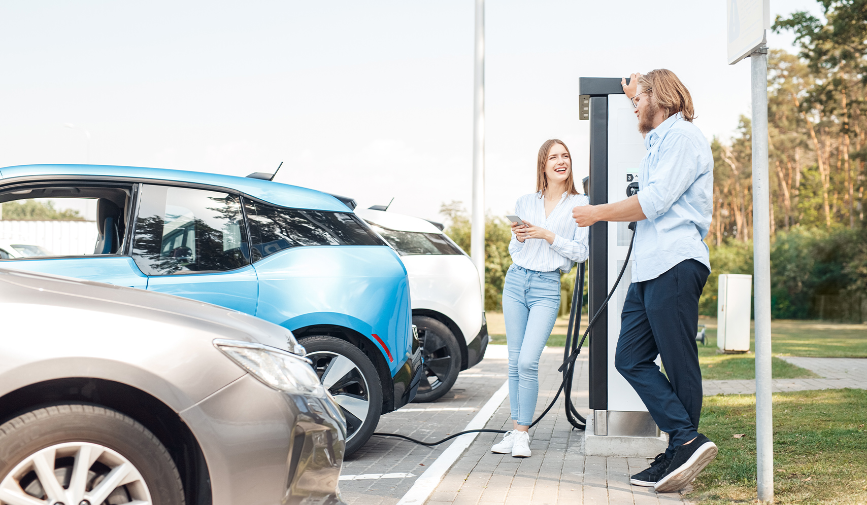 a man and woman standing next to a charging station
