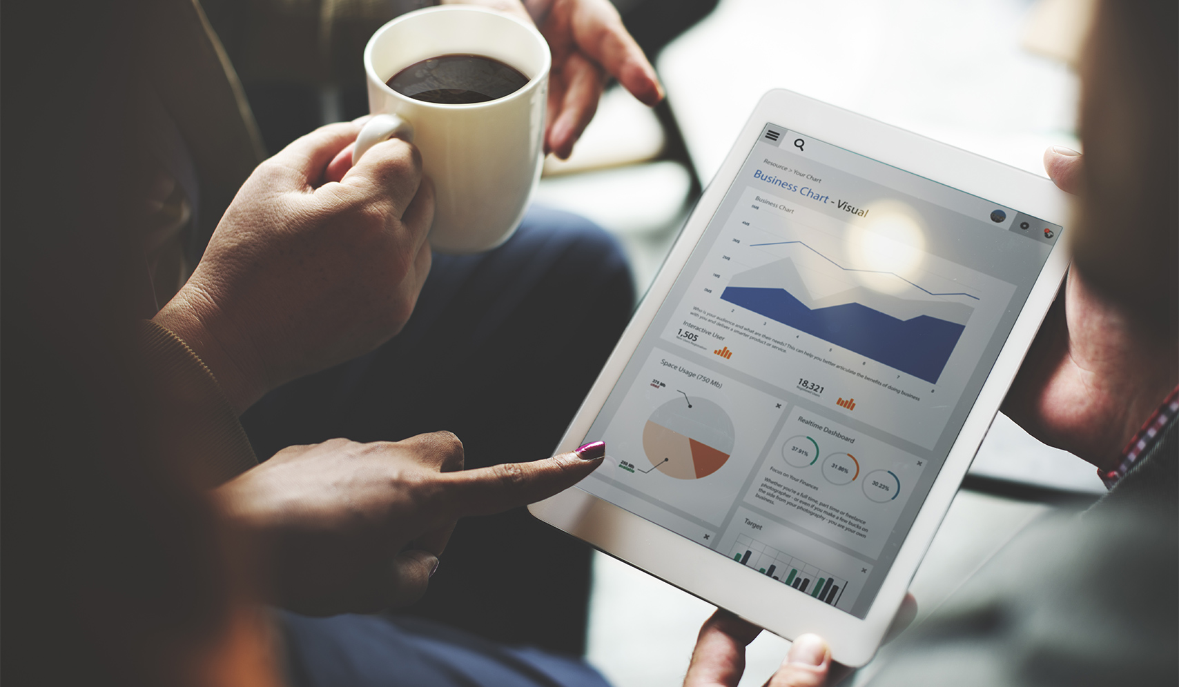 a person holding a cup of coffee and pointing at a tablet