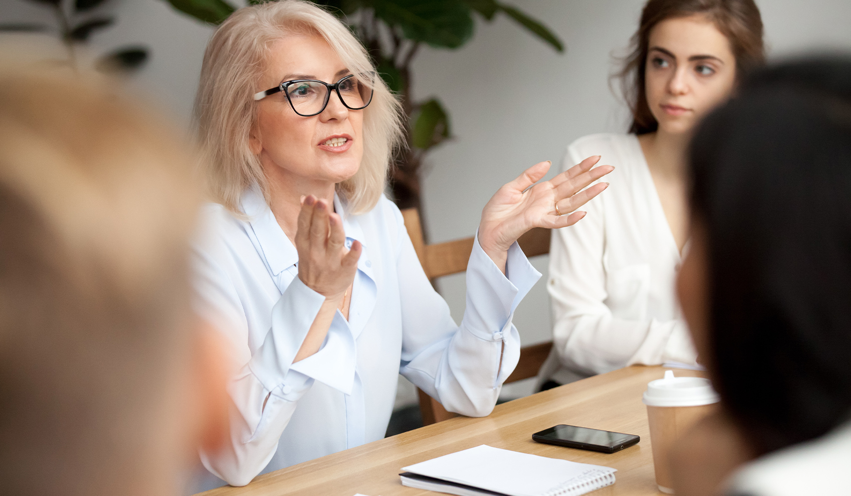 a woman sitting at a table with her hands raised