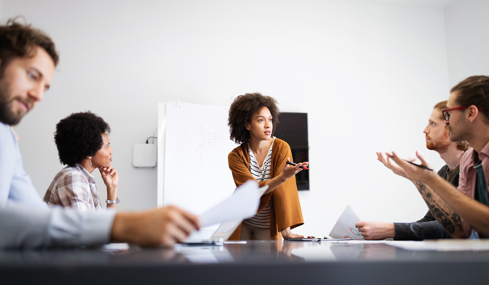 a woman standing in front of a table with people in the background