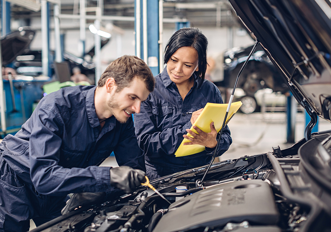 a man and woman working on a car