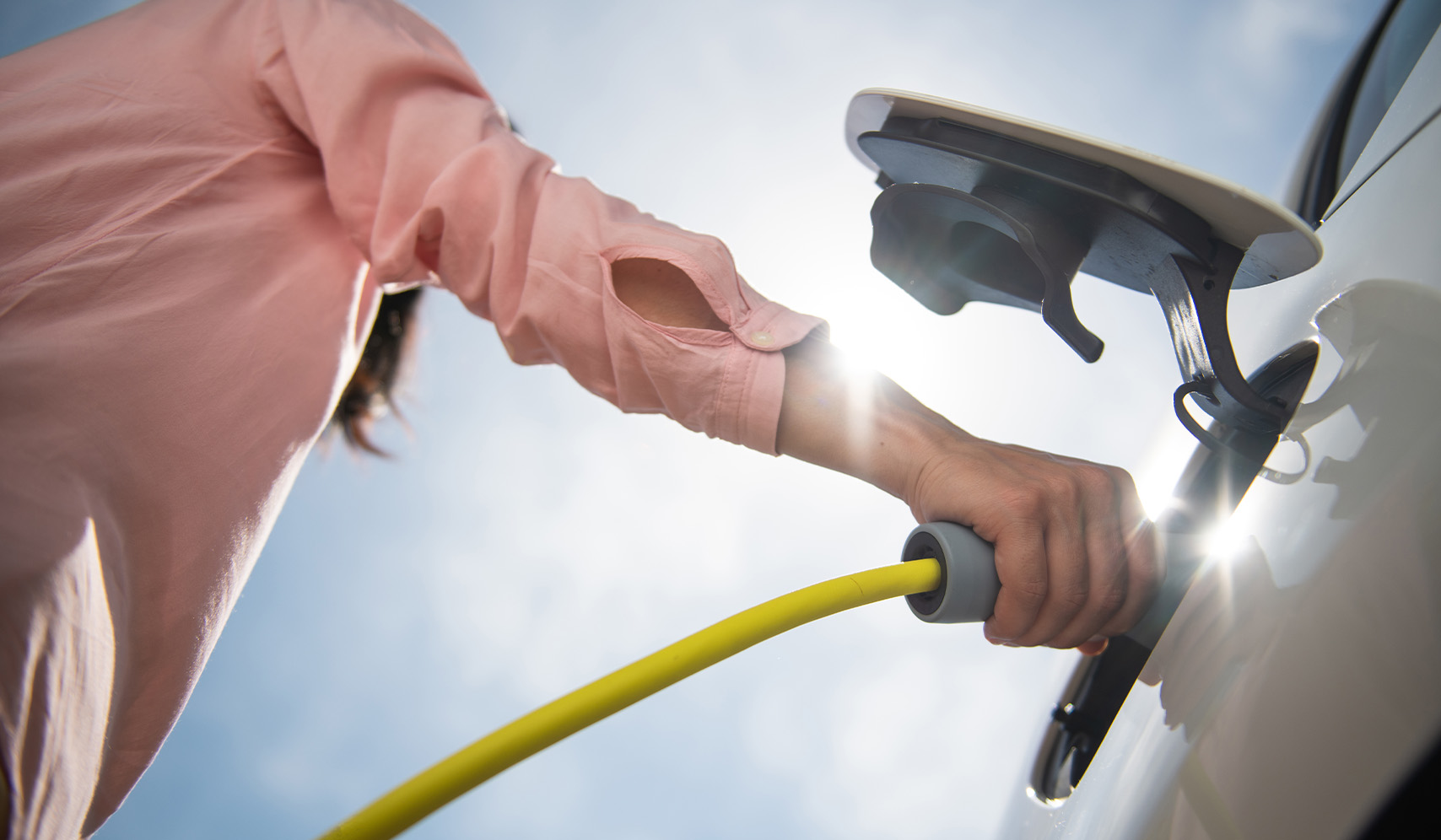 a person holding a yellow hose to a car