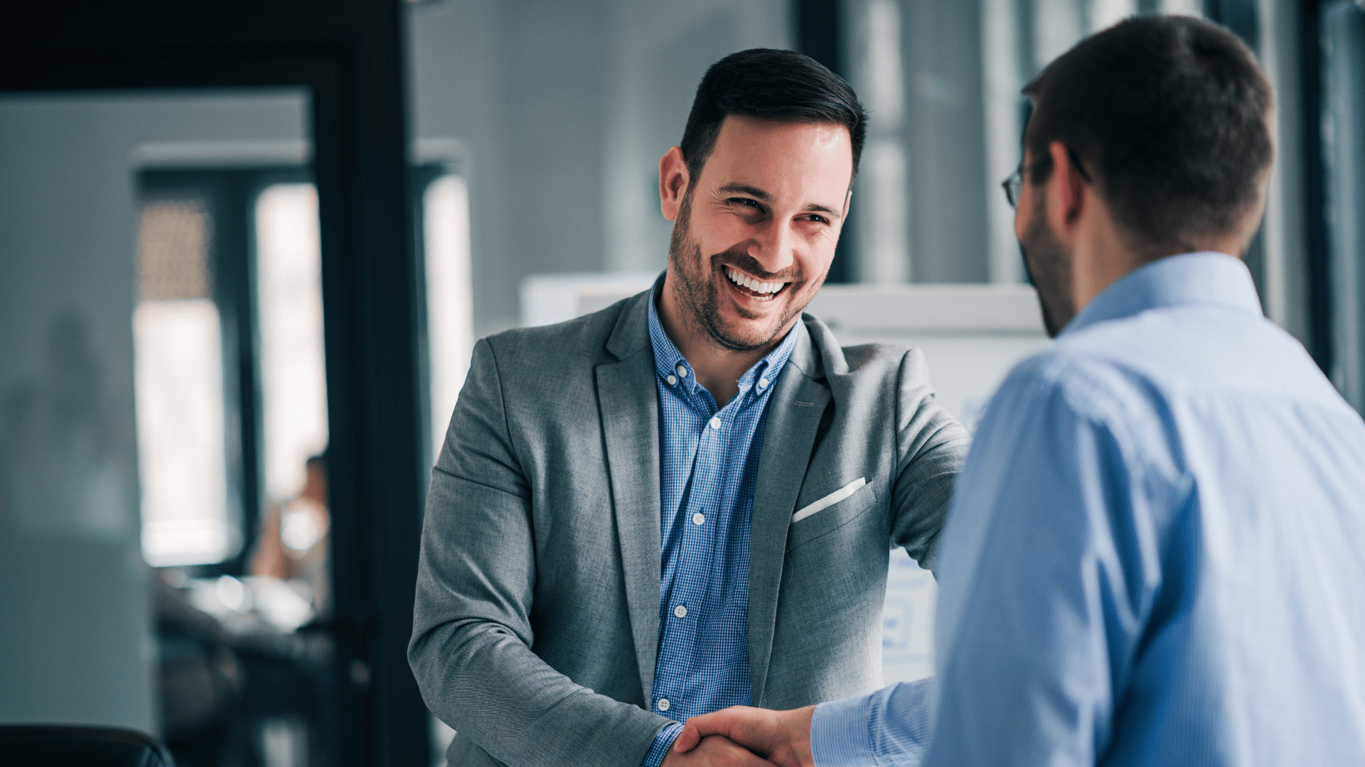 a man in a suit shaking hands with another man in a room