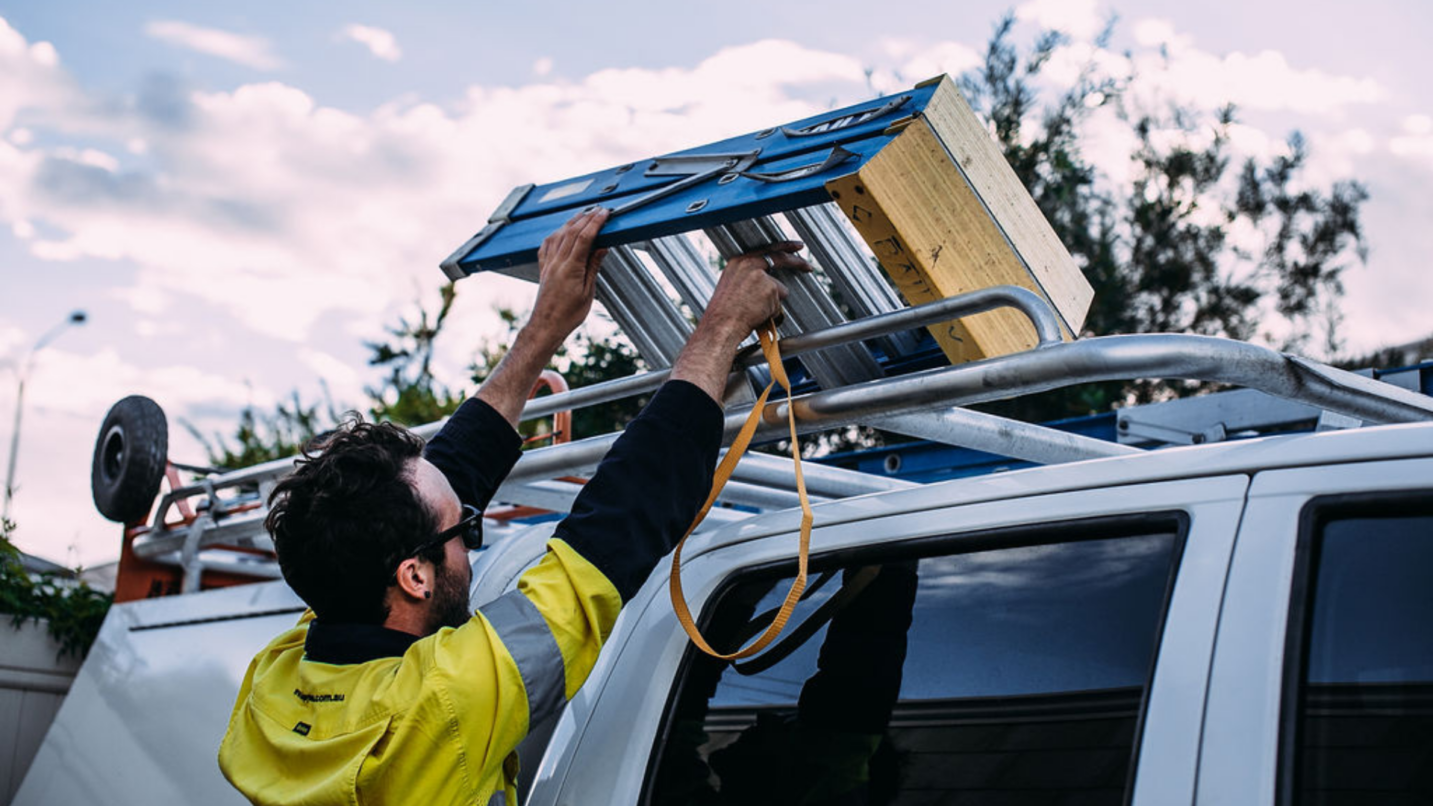 a man holding a ladder on top of a truck