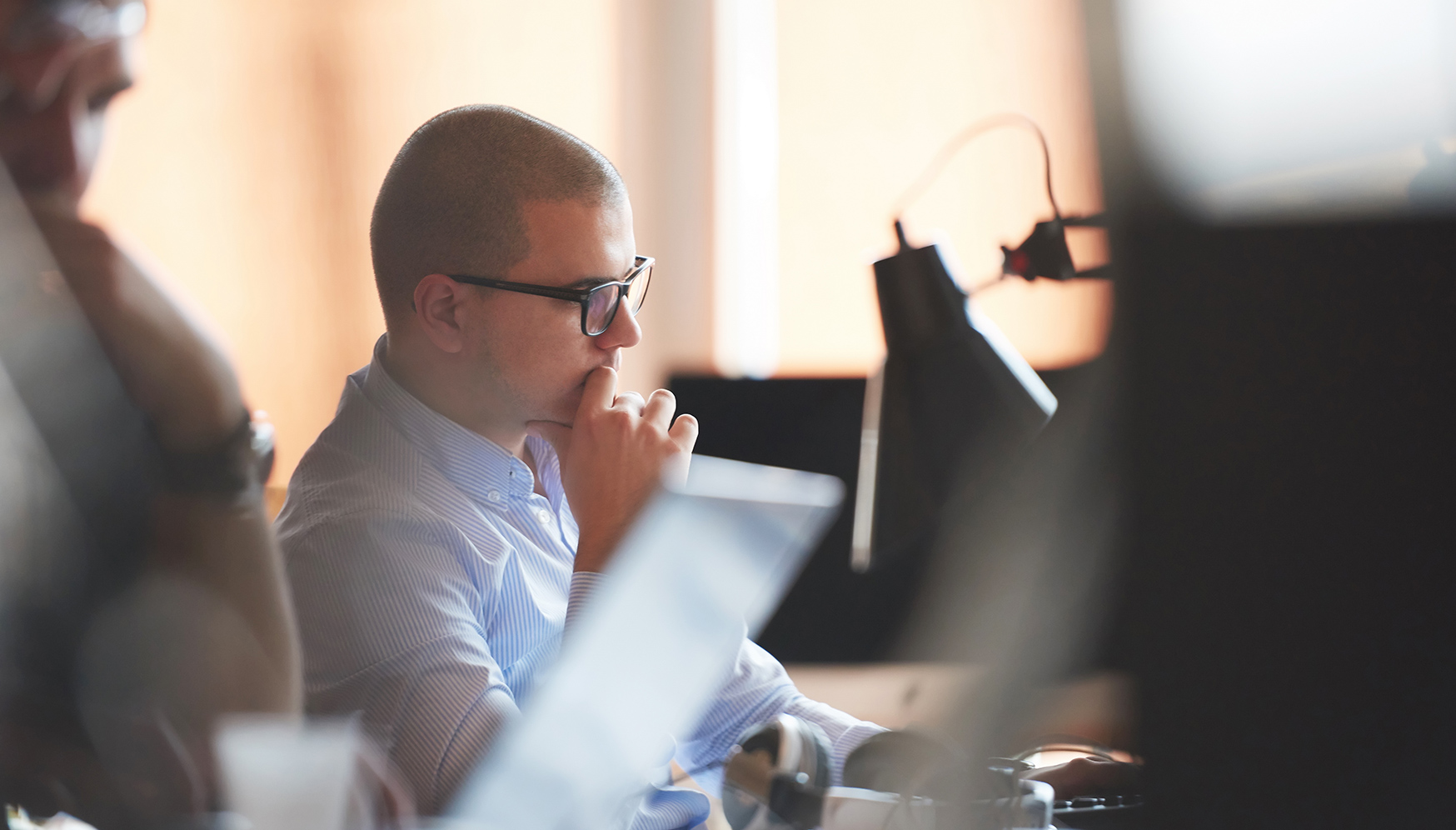 a man sitting at a desk with his hand on his chin