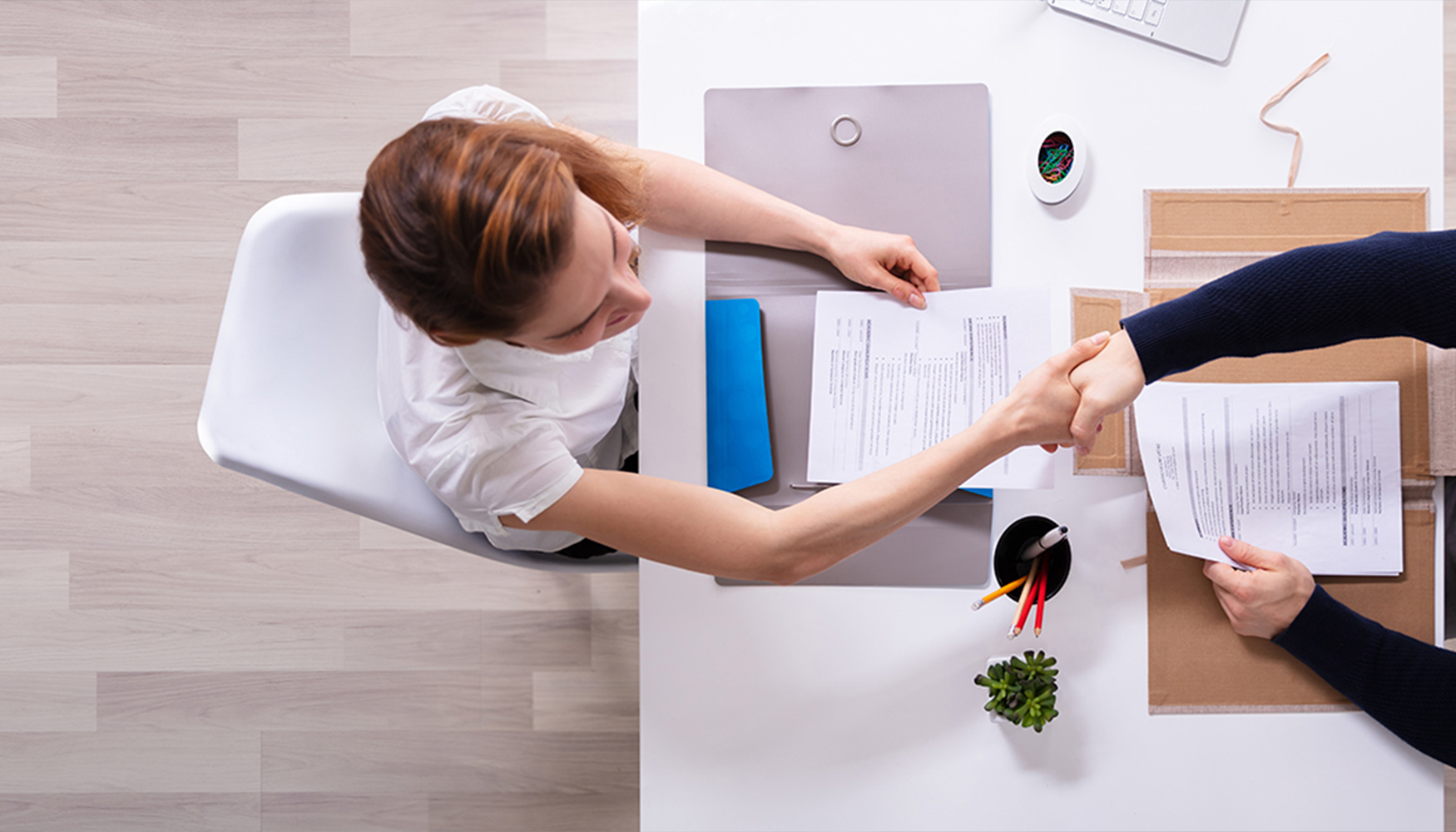 a woman shaking hands with a man at a desk