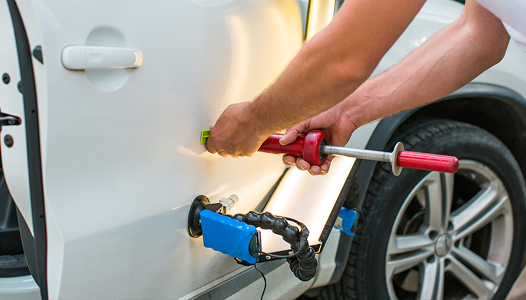 a person holding a tool to a car