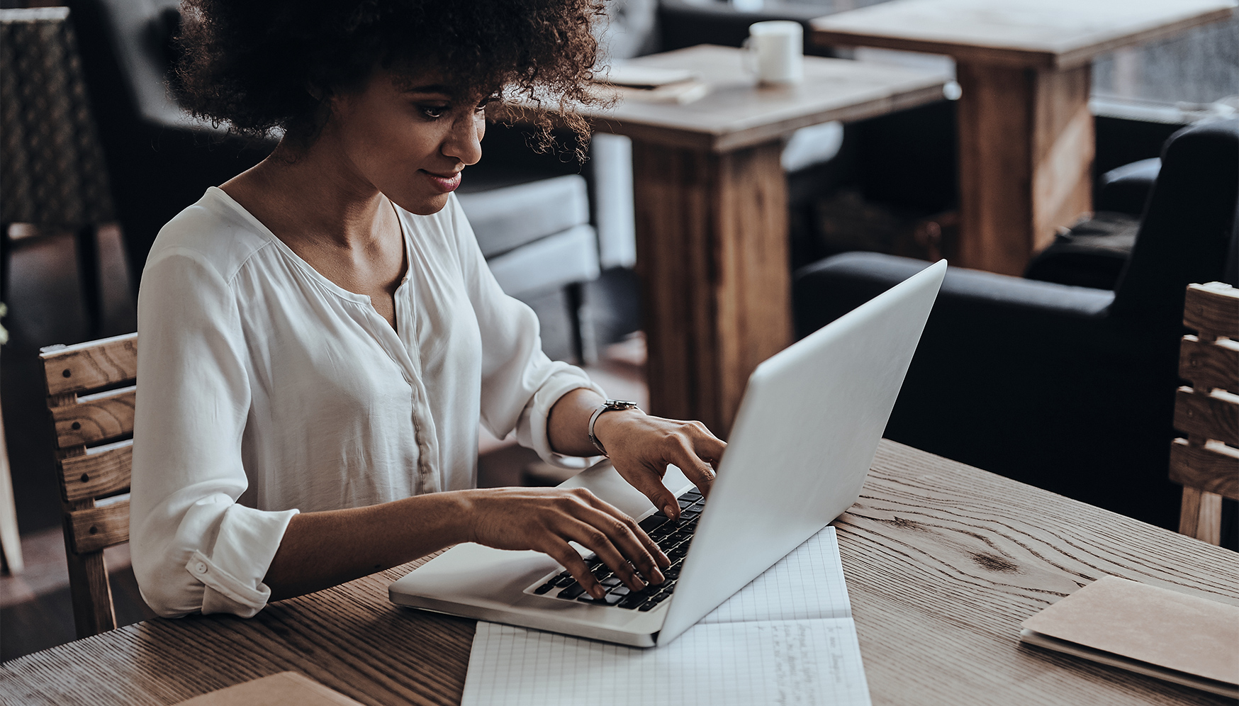 a woman sitting at a table typing on a laptop