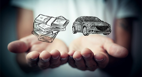 One hand holding a stack of cash and another hand holding a car