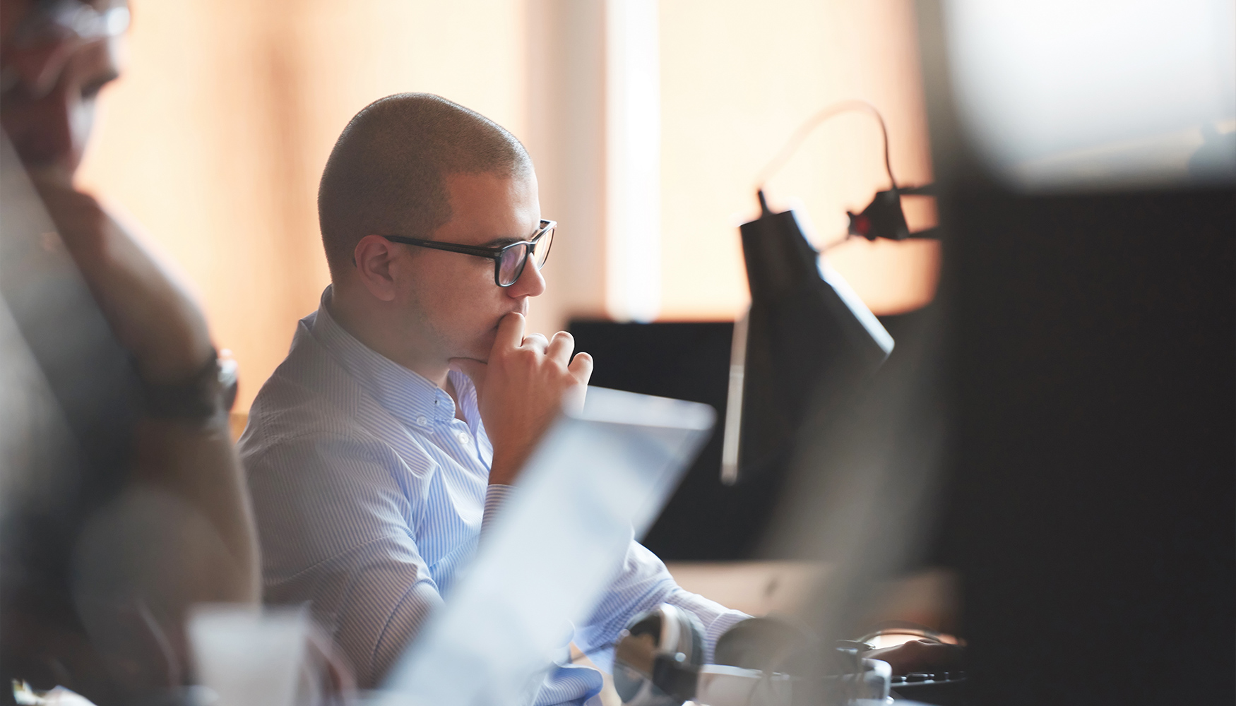 a man sitting at a desk with his hand on his chin