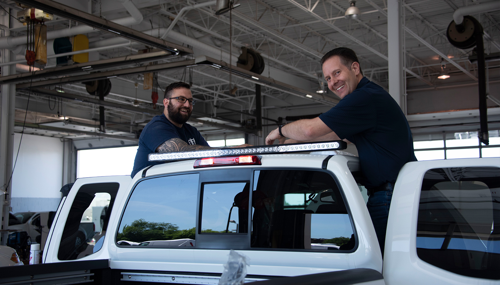 two men standing on top of a white truck
